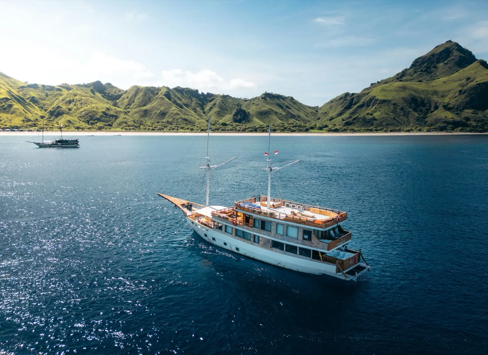 A phinisi at anchor off a green island in Komodo National Park